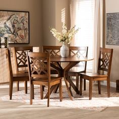 a dining room table with four chairs and a vase on top of it in front of a window