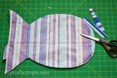 a pair of scissors sitting on top of a piece of fabric next to a fish