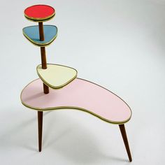 three tiered table with different colored sections on each side and wooden legs, against a white background