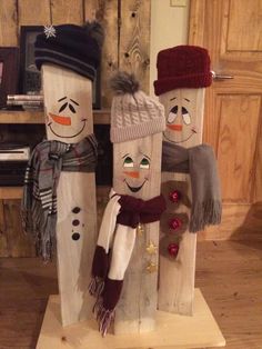 three snowmen made out of wooden planks with hats and scarves