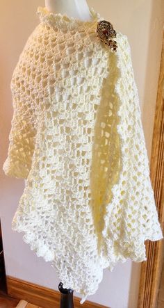 a white crocheted shawl is on display