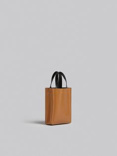 North/South tote bag, nano size, in calf leather with internal slot pocket. Leather top handles and detachable shoulder strap, adjustable with buckle. Colorblocked design. Gold hardware. Gold printed logo outside. Square Leather Bucket Bag With Detachable Strap, Leather Square Bucket Bag With Detachable Strap, Minimalist Leather Box Bag With Removable Pouch, Square Leather Satchel With Handle Drop, Leather Square Satchel With Handle Drop, Rectangular Calf Leather Bucket Bag For Work, Modern Rectangular Calf Leather Bucket Bag, Designer Rectangular Bucket Bag For Workwear, Minimalist Square Leather Box Bag