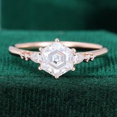 an engagement ring with three diamonds on it, sitting on top of a green velvet