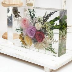 a glass block with flowers in it sitting on a table