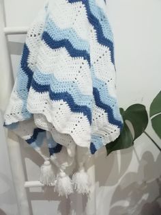 a blue and white blanket sitting on top of a chair next to a potted plant