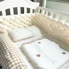 a white crib with pillows and blankets on it