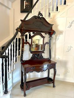 an old fashioned wooden vanity with mirror on it's stand next to the stairs