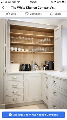 a kitchen with white cabinets and glassware on the shelves