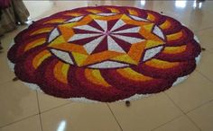 a large flower arrangement on the floor in a room with people standing around and looking at it