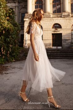 a woman in a white dress is walking down the street