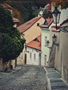 an old cobblestone street leading up to some white buildings with red roof tops