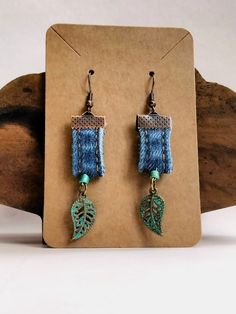 the earrings are made with blue thread and green leaf charms on each earwires