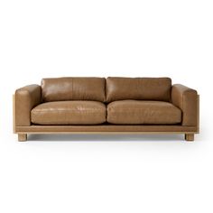 a brown leather couch sitting on top of a wooden frame