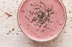 a pink smoothie in a glass with sprinkles on top