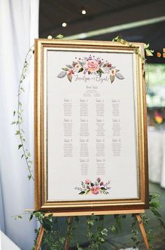 a wedding seating chart is displayed in front of a white backdrop with greenery and flowers