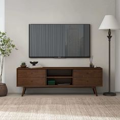 a living room with a large flat screen tv mounted on the wall above a wooden entertainment unit