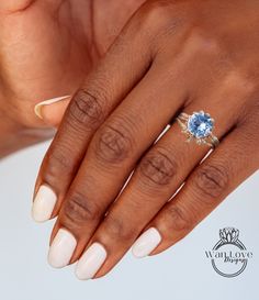 a woman's hand with white nails and an oval blue ring on her finger