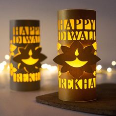 two lit up candles with the words happy diwali written on them, sitting next to each other