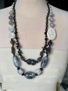 Elegant harmony of grades of black/ grays  and white in a natural look stones, mixture of sizes of beads , pearls and stones that creates a contrast of a beautiful streamlined necklace in tow rows, adorned with huge white natural stone, finished with an adjustable silver color chain. Stones Necklace, Colored Stones, Marble Colors, Grey Stone, Stone Necklace, Natural Stone, Stone Color, Silver Color, Grey And White