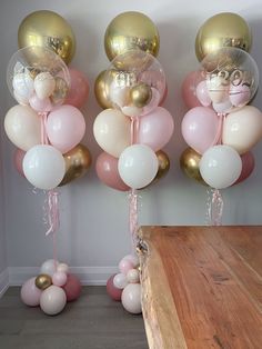 some balloons are hanging from the ceiling and pink, white and gold balloons have been tied to them