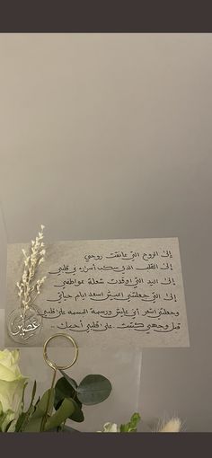 a bouquet of flowers sitting next to a piece of paper with writing on it