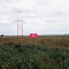 a red sign sitting on the side of a lush green field