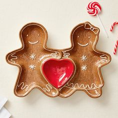 two gingerbread cookies with candy canes on the side and one in the shape of a heart