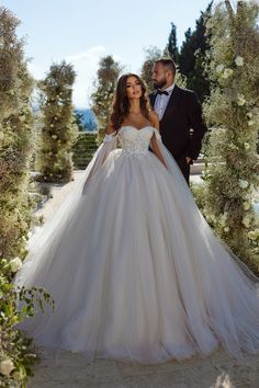 a bride and groom posing for a photo in front of an archway decorated with flowers