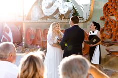 Capture the magic of a Neon Museum wedding ✨. The bride, in a timeless wedding dress with elegant lace sleeves, gazes adoringly at her groom. Golden hour casts a romantic glow, while vintage neon signs create a vibrant backdrop. A dreamy bokeh effect enhances the enchanting moment 💖. Witness this unique celebration of love and style! #weddinghairstyles #longsleeveweddingdress #weddingdress #neonmuseumwedding #wedding Golden Hour Wedding, Bokeh Effect