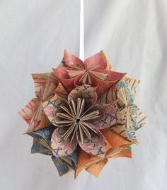 an origami flower is hanging from a string on a white background with other paper flowers