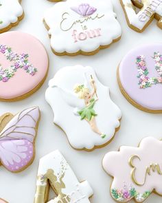 decorated cookies are arranged in the shape of letters and fairy characters on white paper with gold trimmings