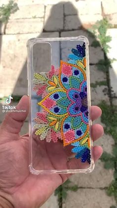 someone is holding up their phone case with colorful beads on it