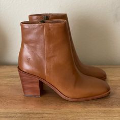 a pair of brown leather ankle boots sitting on top of a wooden table next to a white wall