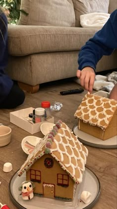 two people are decorating a gingerbread house