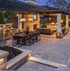 an outdoor kitchen and dining area at night with lights on the tables, benches and grill