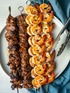 shrimp and praw skewers on a white plate with a blue towel next to them