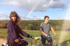 two people on bicycles with a rainbow in the background