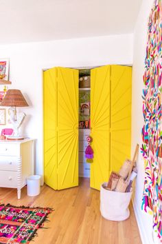 a room with yellow doors and rugs on the wooden floor next to a white dresser