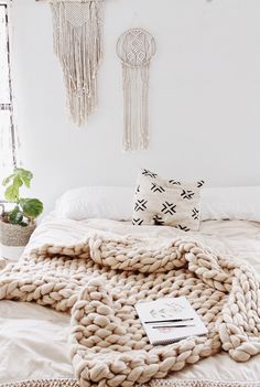 a bed with a blanket and pillows on top of it next to a potted plant