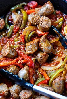 sausage and peppers are being cooked in a skillet with tongs on the side