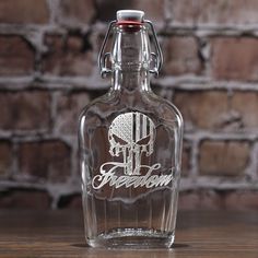 an empty glass bottle sitting on top of a wooden table next to a brick wall