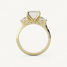 a yellow gold engagement ring with three stones on the side and an oval shaped center stone