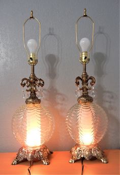 two glass lamps sitting on top of a wooden table