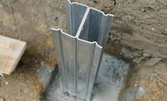 an open metal pipe sticking out of the ground next to a concrete slab and cement block