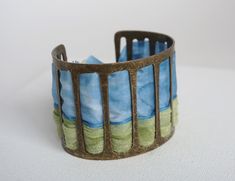 This cuff bracelet is in blue and green hand painted silk and bronze colored metal * bronze and silk colored metal * width 5 cm * 17 cm in length * High quality French paintings *Heat fixed to preserve colors * Made in Lyon * blue, chartreuse green, bronze * bohemian It's the perfect useful gift to give to please Mother's Day, Wedding Anniversary, Birthdays Sending : beautifully packaged in an organza bag and in a black gift box sent by colissimo to France My store: https://www.etsy.com/fr/shop/ French Paintings, Green Bracelet, Chartreuse Green, Green Hand, Painted Silk, Jewelry Blue, Hand Painted Silk, Black Gift Boxes, Black Gift