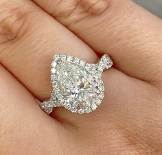 a woman's hand with a diamond engagement ring on top of her wedding band