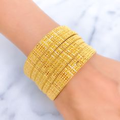 Indulge in luxury with our Royal Floral Checkered 22K Gold Bangle Set. Crafted in 22k gold, this exquisite set features a total weight of 92.5g, radiating opulence. The captivating floral checkered design and lustrous yellow gold finish make it a statement of high fashion. Bangle Size 2.7 with a 2.45" diameter opening. Set includes 6 stunning bangles PRODUCT DETAILS Gold Purity(karat): 22k Gold Weight(grams): 92.5 Item Finish: Yellow Gold Bangle Size: 2.7 Bangle Opening(diameter): 2.45" Number O Yellow Gold-plated Bangle As Gift, Yellow Gold-plated Bangle For Gift, Yellow Gold Plated Bangle For Gift, Yellow Gold Plated Bangle As A Gift, Luxury 22k Gold Yellow Jewelry, Yellow Gold-plated Bangle Jewelry, Yellow Gold-plated Bangle Bracelet, Luxury Gold Bangle For Festive Season, Gift 22k Gold Yellow Bangle