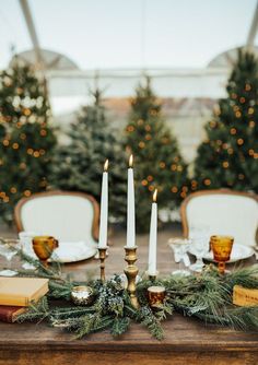 the table is set with candles, books and other decorations for an elegant christmas dinner