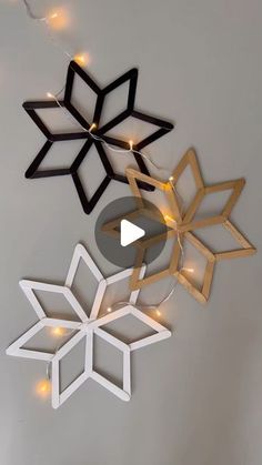 three paper snowflakes hanging from the ceiling with string lights on them, one is black and one is white