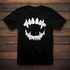 Unleash your inner nocturnal elegance with our Vampire Fangs T-shirt. Embrace the dark allure of the night with this edgy design featuring distressed vampire fangs that add a touch of mystery and rebellion. Perfect for those who have a taste for gothic fashion and a penchant for the supernatural. Elevate your wardrobe with this uniquely distressed tee that bites back. Product Features: 100% cotton (fiber content may vary for different coulors) Medium fabric (5.3 oz/yd² (180 g/m Classic fit Tear-away label Runs true to size Washing care instructions: Following these instructions will Keep the black more vivid and help avoid fading, cracking and shrinking of the garment. WASH: Printed apparel should be machine-washed cold, inside-out on a gentle cycle with a mild detergent. DRY: Printed appa Gothic Black T-shirt For Halloween, Edgy Halloween T-shirt For Alternative Fashion, Edgy Halloween T-shirt With Screen Print, White Gothic T-shirt For Streetwear, Black Halloween Concert T-shirt, Alternative Halloween Graphic T-shirt, Gothic Short Sleeve T-shirt For Halloween, Edgy Halloween Graphic Tops, Gothic Graphic T-shirt For Streetwear